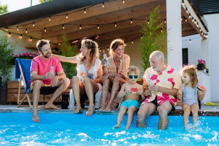 Photo for A multi generation family enjoying summer time and sitting at backyard pool. - Royalty Free Image