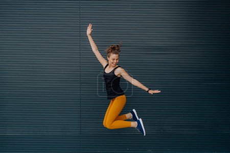 Foto de Retrato de una joven excitada saltando al aire libre en una ciudad. - Imagen libre de derechos