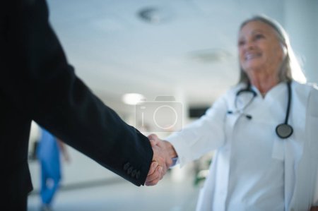 Photo for Close-up of handshake of doctor and business person. - Royalty Free Image