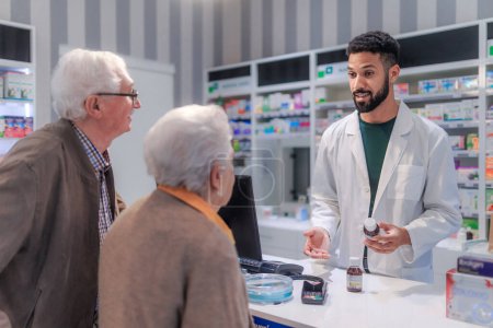 Photo for Young pharmacist selling medications to senior couple in a pharmacy store. - Royalty Free Image