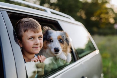 Photo for Little girl and her dog sitting in a car, prepared for a family trip, - Royalty Free Image