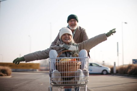 Photo for Senior couple going home from a grocery store, having fun. - Royalty Free Image
