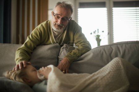 Foto de Hombre mayor cuidando de su nieta enferma. - Imagen libre de derechos