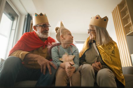 Téléchargez les photos : Grand-parents jouant avec leur petite-fille, ayant des costumes de roi et de reine. - en image libre de droit
