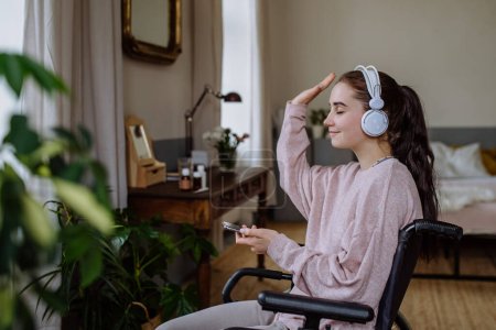Téléchargez les photos : Jeune fille écoute musique auge écouteurs dans une chambre. - en image libre de droit