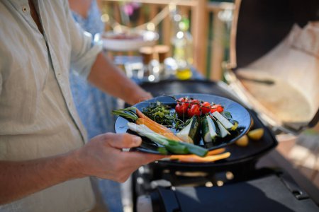 Foto de Un hombre irreconocible asar verduras a la parrilla durante la fiesta de verano del jardín familiar. - Imagen libre de derechos