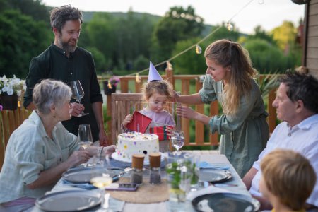 Téléchargez les photos : Une famille multi-génération fête son anniversaire et organise une fête de jardin dans la cour arrière sur le patio. - en image libre de droit