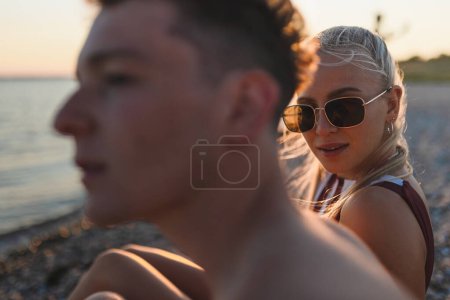 Photo for Young couple spending time at lake, during sunset. - Royalty Free Image