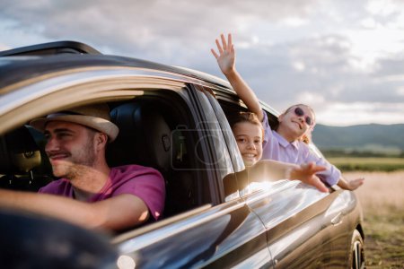 Foto de Familia feliz disfrutando de conducir en su coche eléctrico. - Imagen libre de derechos