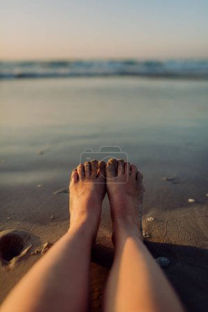 Close-up of woman with her feet on the beach.