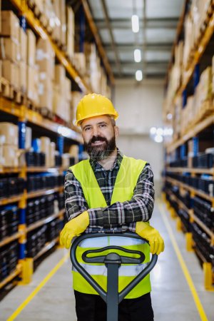 Photo for Male warehouse worker pushing the pallet truck. - Royalty Free Image