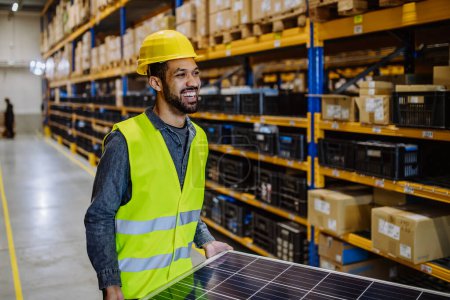 Photo for Portrait of warehouse worker carring a solar panel. - Royalty Free Image