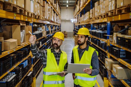Téléchargez les photos : Warehouse workers checking stuff in warehouse with digital system in a tablet. - en image libre de droit