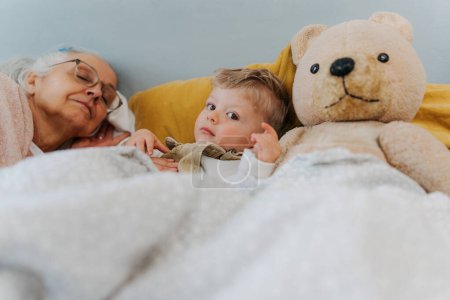 Téléchargez les photos : Grand-mère couchée avec son petit-fils dans un lit. - en image libre de droit