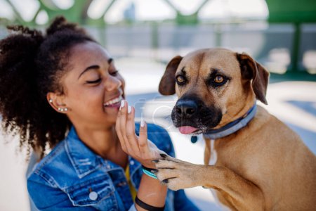 Téléchargez les photos : Multiracial girl sitting and resting with her dog outside in the bridge, training him, spending leisure time together. Concept of relationship between a dog and teenager, everyday life with pet. - en image libre de droit
