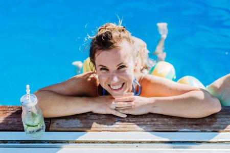 Photo for Young woman enjoying summer time in an outdoor pool. - Royalty Free Image