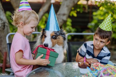 Foto de Pequeños niños y su perro en la celebración de la fiesta de cumpleaños. - Imagen libre de derechos