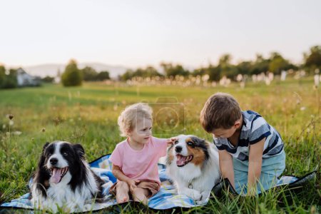 Photo for Little children with dogs outdoor, having picnic. - Royalty Free Image
