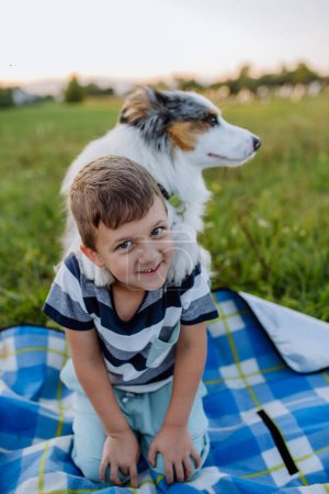 Foto de Niño pequeño con perro al aire libre, teniendo picnic. - Imagen libre de derechos