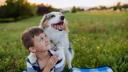 Foto de Niño pequeño con perro al aire libre, teniendo picnic. - Imagen libre de derechos