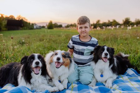 Foto de Niño pequeño con tres perros al aire libre, teniendo picnic. - Imagen libre de derechos