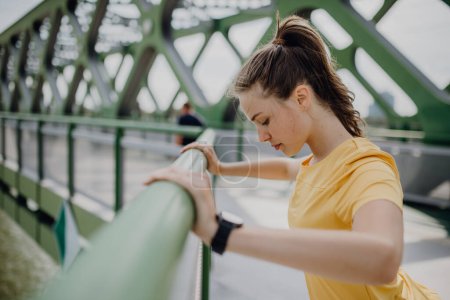 Young woman doing stretching in a city, preparing for run, healthy lifestyle and sport concept.
