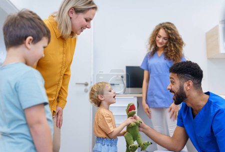 Photo for Young multiracial dentist playing with kids at his office in dentist clinic. - Royalty Free Image