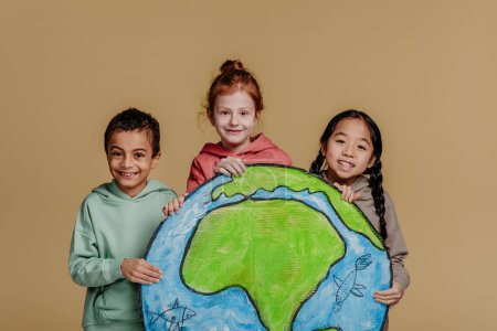 Téléchargez les photos : Portrait de trois enfants avec modèle de la Terre, tournage en studio. Concept de diversité dans une amitié. - en image libre de droit