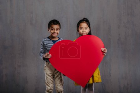 Photo for Studio shoot of little boy and girl holding paper heart. - Royalty Free Image