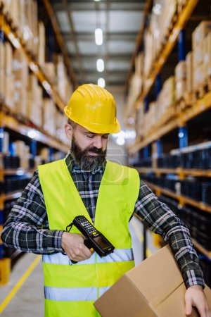 Photo for Warehouse worker stocking goods in warehouse. - Royalty Free Image