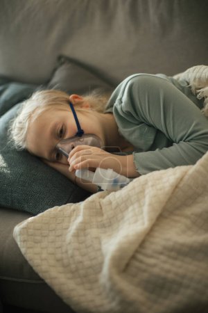 Foto de Little niña enferma usando un inhalador durante la gripe. - Imagen libre de derechos
