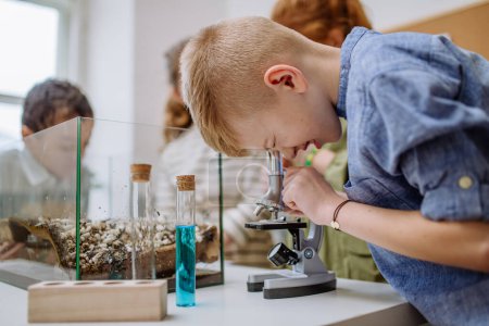 Photo for Little boy looking in a microscope during science lesson. - Royalty Free Image