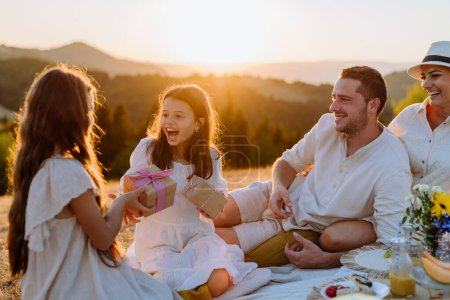 Téléchargez les photos : Happy family with children having picnic in nature,celebratig, giving each other gifts. - en image libre de droit