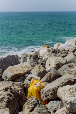 Téléchargez les photos : Garbare sur la plage de pierre, près de l'océan. - en image libre de droit