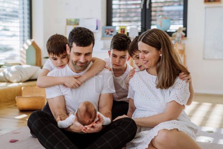 Gran familia con cuatro hijos disfrutando de su bebé recién nacido.