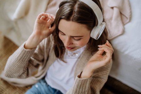 Photo for Young woman listening music trough headphones in the apartment. - Royalty Free Image