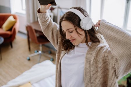 Téléchargez les photos : Jeune femme écoutant de la musique avec des écouteurs dans l'appartement. - en image libre de droit
