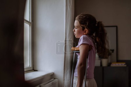 Photo for Little girl with broken leg looking trough the window. - Royalty Free Image