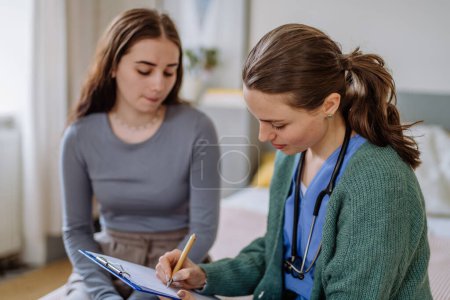Photo for Teenage girl having stomach ache, young woman doctor examining her. - Royalty Free Image