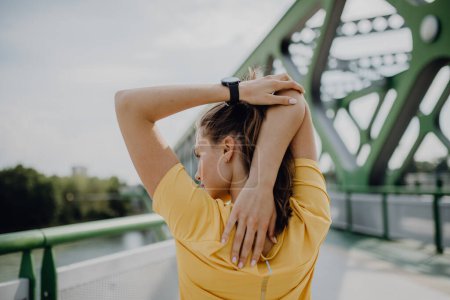 Young woman doing stretching in a city, preparing for run, healthy lifestyle and sport concept.