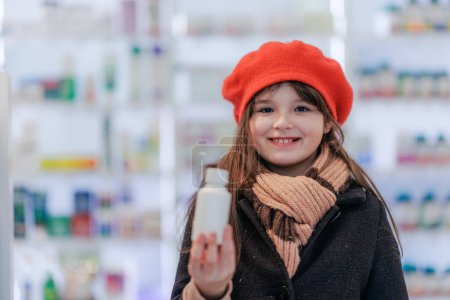 Téléchargez les photos : Portrait de petite fille tenant des médicaments dans un magasin de pharmacie. - en image libre de droit
