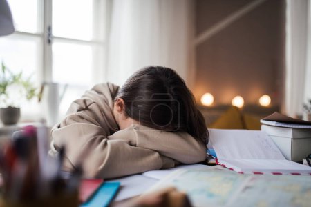 Photo for Unhappy girl doing a homework in her room. - Royalty Free Image
