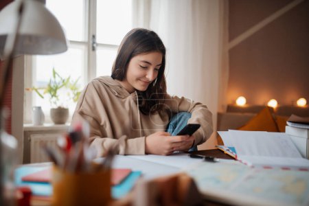 Téléchargez les photos : Jeune adolescente étudiant et faisant ses devoirs dans sa chambre. - en image libre de droit