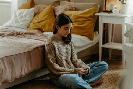 Téléchargez les photos : Adolescente malheureuse assise sur le sol dans sa chambre, koncept de santé mentale. - en image libre de droit