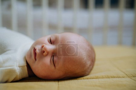 Foto de Vista lateral del bebé recién nacido dormido en la cama pequeña. - Imagen libre de derechos