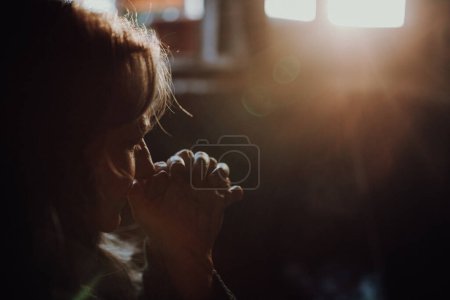 Photo for Close-up of sad elderly woman praying, black background. - Royalty Free Image