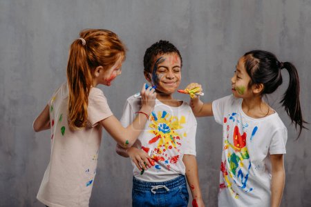 Porträt glücklicher Kinder mit Fingerfarben und bemalten T-Shirts.