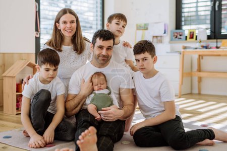 Retrato de una gran familia con cuatro hijos disfrutando de su bebé recién nacido.