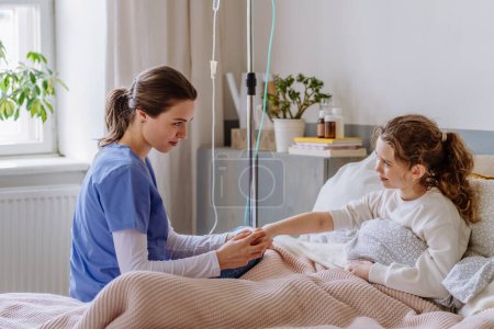 Foto de Enfermera joven cuidando de una adolescente en una habitación de hospital. - Imagen libre de derechos