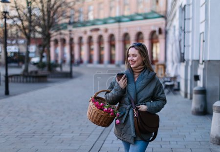 Photo for Young woman in a city with a basket full of flowers. - Royalty Free Image
